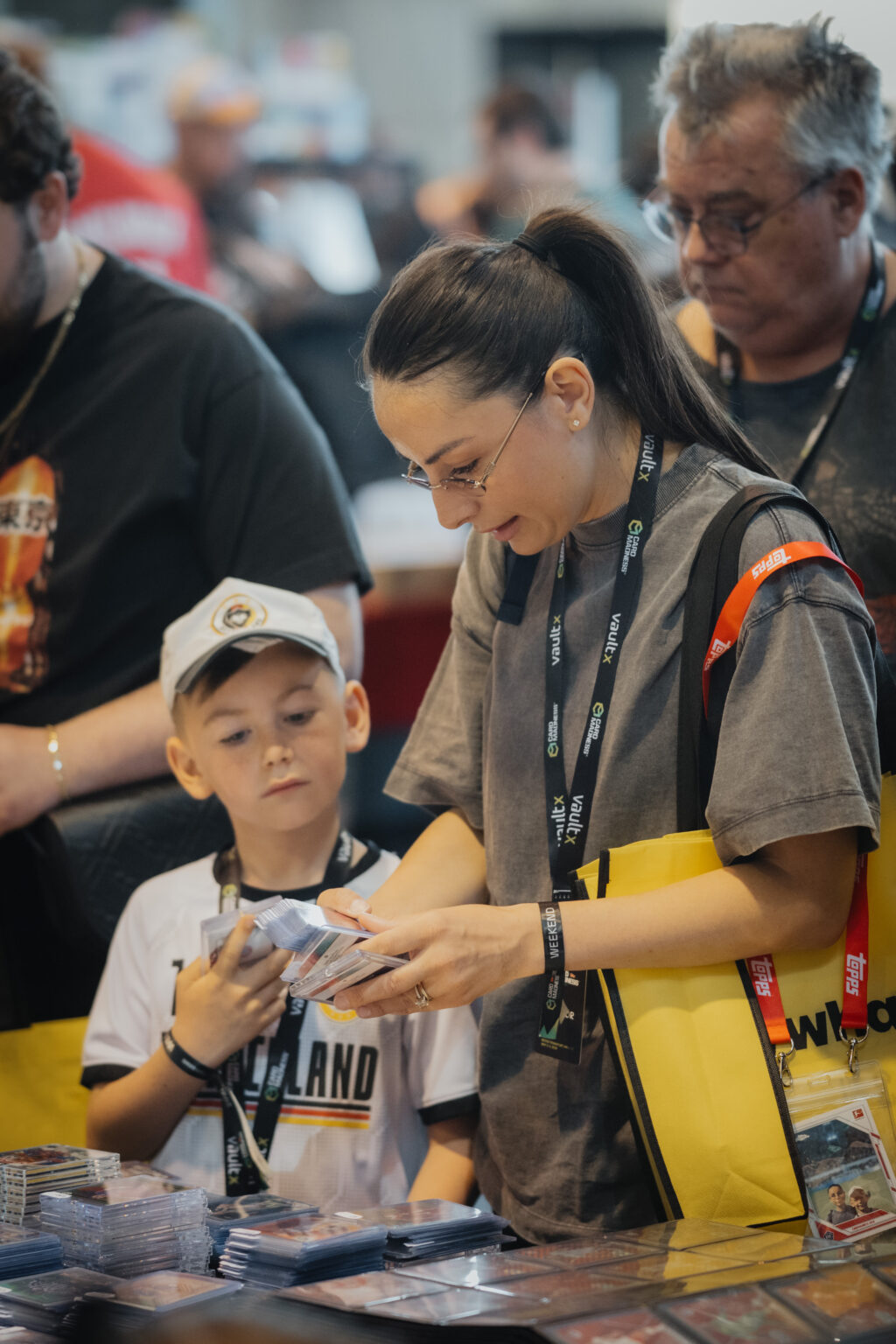 Mother and son sorting trading cards at a dealer table during CARDMADNESS