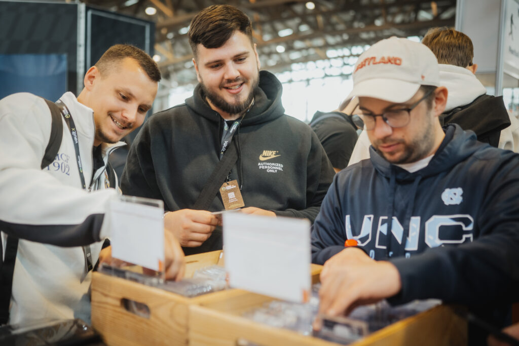 Three collectors searching through a box of cards at CARDMADNESS
