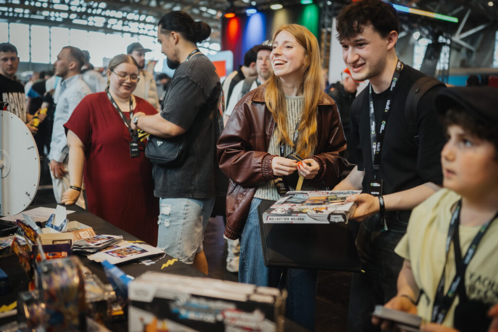 Families and collectors browsing trading cards at a dealer table at CARDMADNESS
